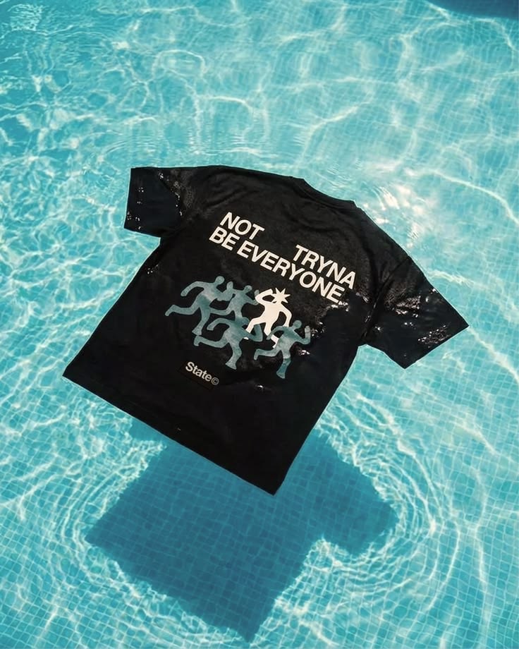 Graphic black T-shirt photographed against turquoise pool water