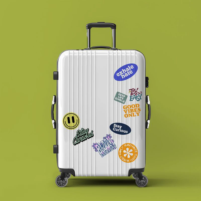 Silver suitcase with colourful stickers against a green backdrop